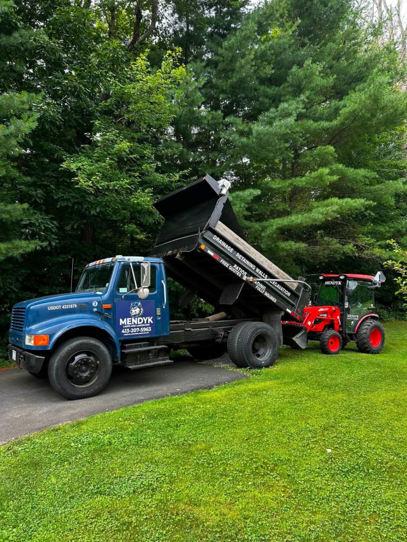 Mendyk Lawn & Landscape truck and tractor on a well-kept residential property