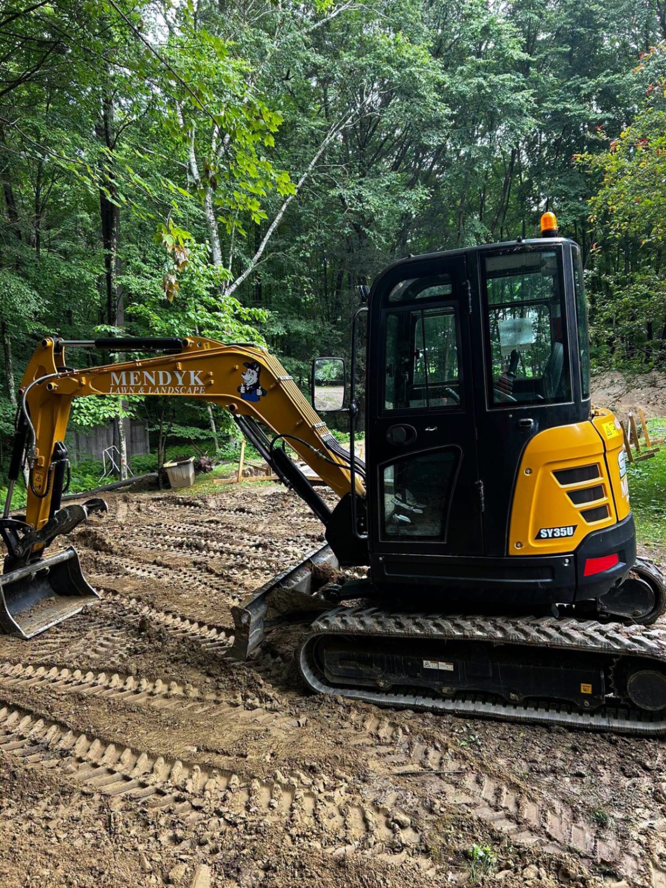 Mendyk mini excavator grading a wooded residential lot